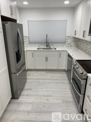 A kitchen with white cabinets and a marble countertop.