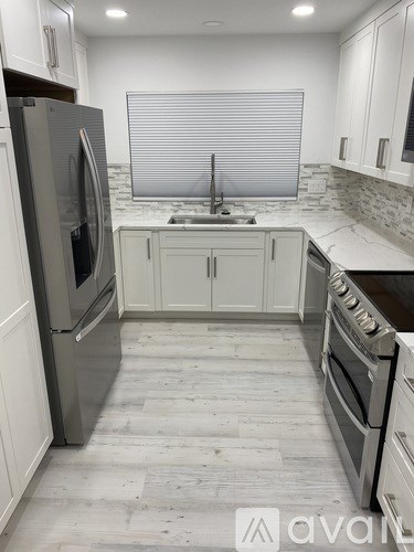 A kitchen with white cabinets and a marble countertop.