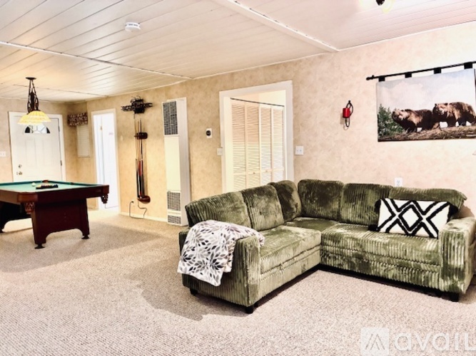 A living room with a pool table and a couch.