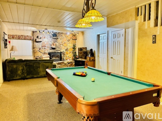 A pool table in a room with a stone wall and a lamp.