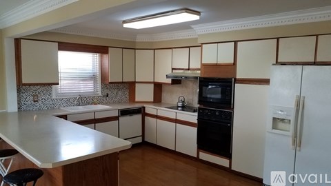 A kitchen with a white counter top and wooden cabinets.