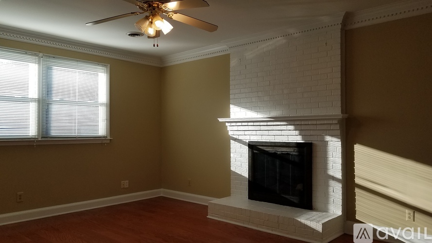 A living room with a fireplace and a ceiling fan.