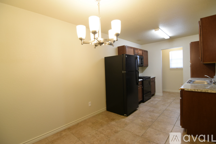 A kitchen with a black fridge and a chandelier.