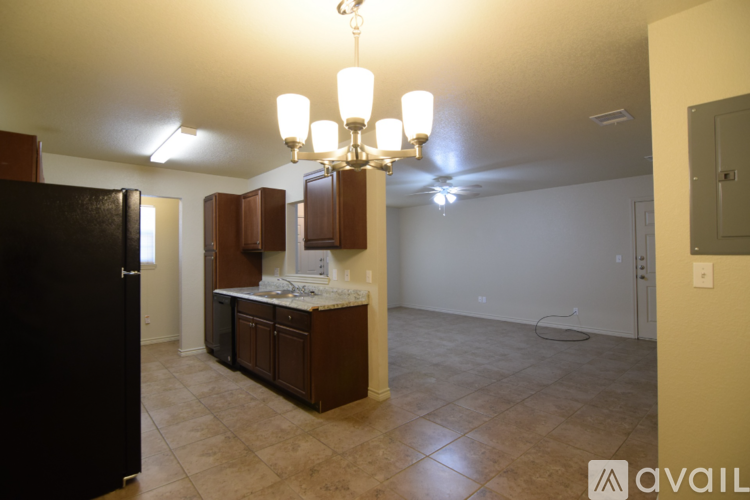 A kitchen with brown cabinets and a black refrigerator.