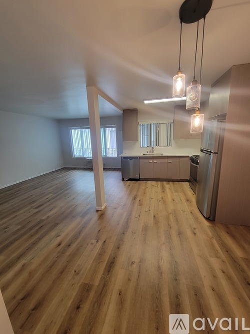 A spacious room with wooden flooring and pendant lights.