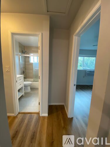 A room with a wooden floor and a white door leading to a bathroom.