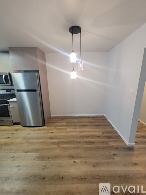 A kitchen with wooden floors and a stainless steel refrigerator.