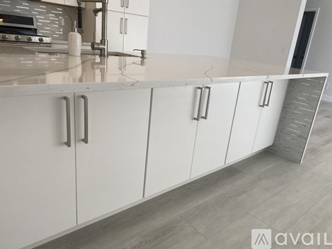 A kitchen with white cabinets and a marble countertop.