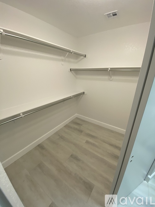 A spacious walk-in closet with wooden floors and white walls.