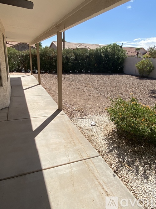 A patio area with a gravel ground and a concrete walkway.