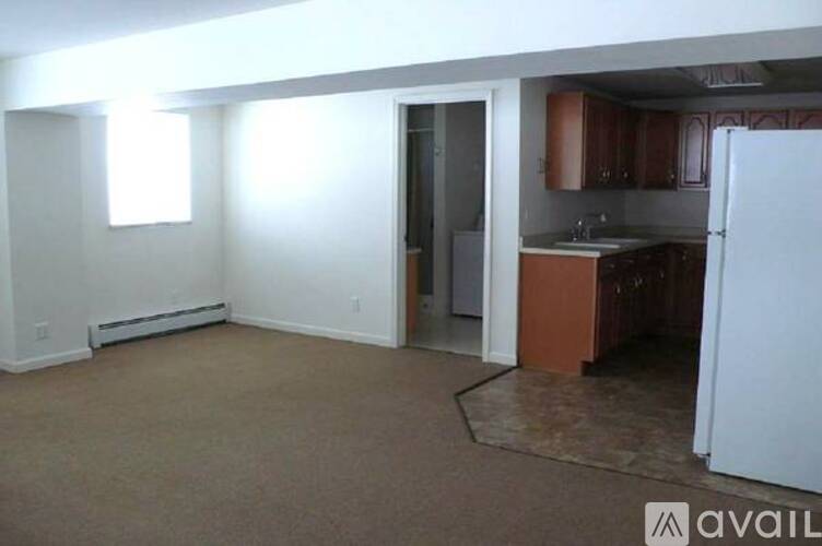 A kitchen area with a refrigerator, sink, and cabinets.