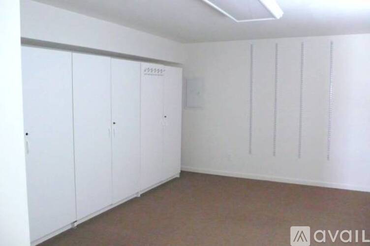 A room with white cupboards and a brown floor.