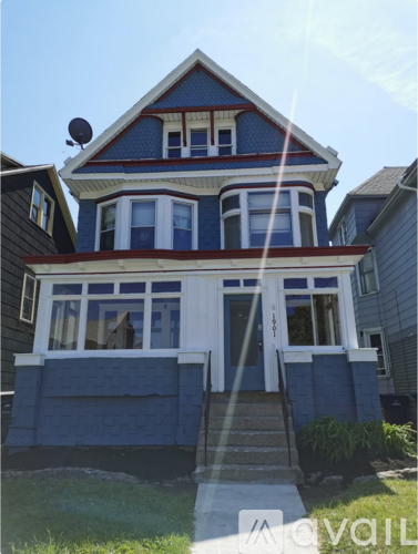 A blue house with white trim and a red roof.