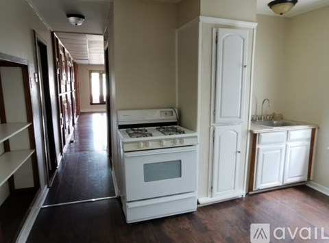 A kitchen with a white stove and cabinets.