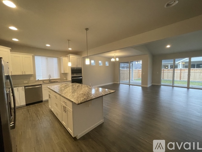 A spacious kitchen with white cabinets and a granite countertop.