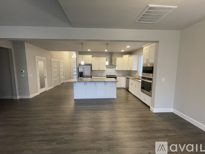 A spacious kitchen with white cabinets and a wooden floor.