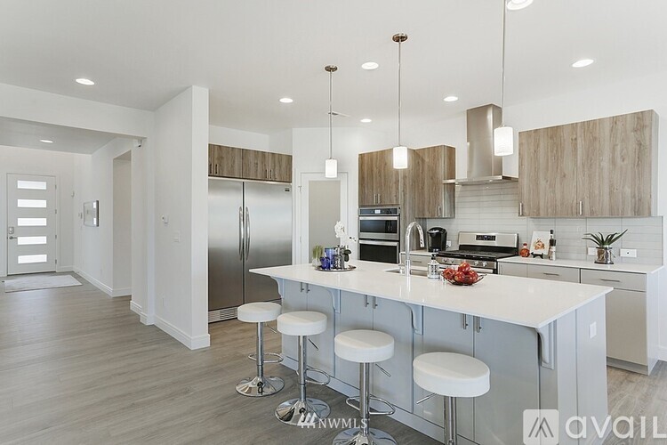 A modern kitchen with a white island and bar stools.