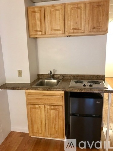 A kitchen with wooden cabinets and a black fridge.