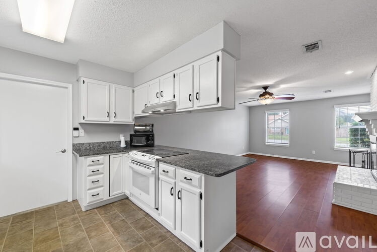 A kitchen with white cabinets and a black countertop.