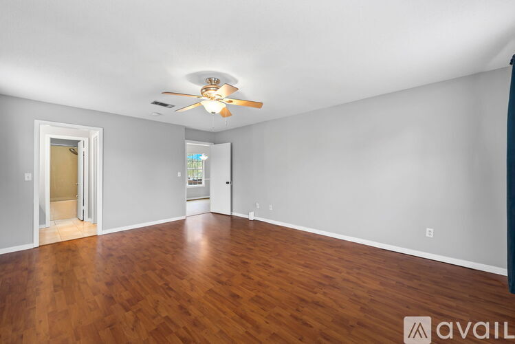 A spacious room with a ceiling fan and hardwood floors.