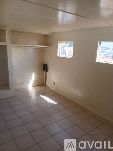 A room with tiled flooring and two windows.