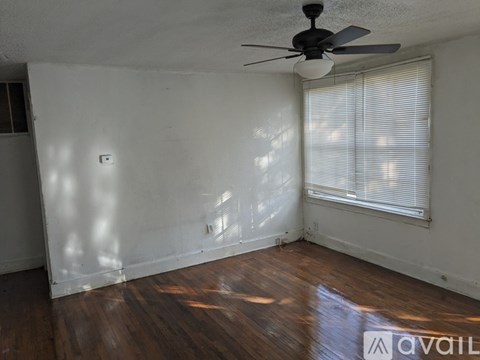 A room with a ceiling fan and a window with blinds.