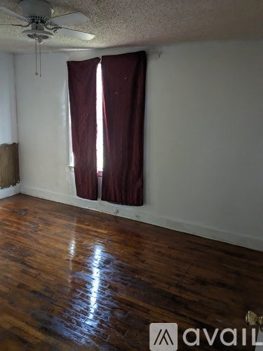 A room with a ceiling fan and wooden floors.