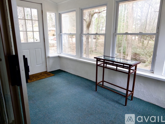 A room with a carpeted floor and a table in front of a window.