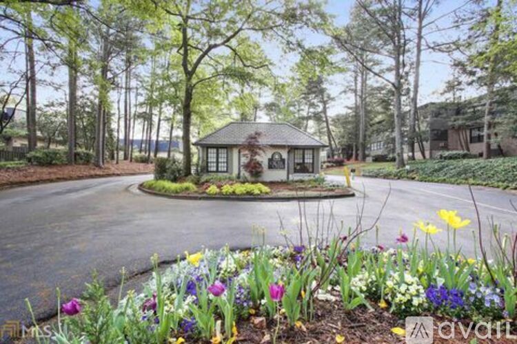 A gazebo is surrounded by a flowerbed and trees.