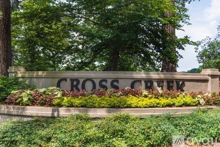 A sign that says Cross Creek in front of some trees.