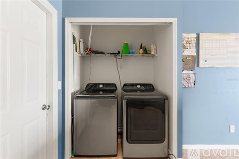 A small kitchen with two ovens and a shelf with various items.