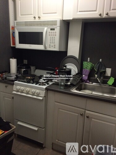 A kitchen with a stove, sink, and cabinets.
