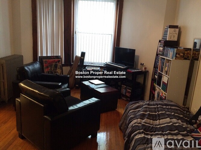 A living room with a couch, chair, ottoman, and a television.