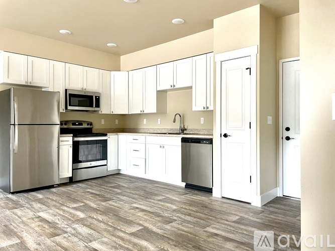 A kitchen with white cabinets and a wooden floor.