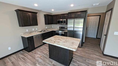 A kitchen with dark wood cabinets and a marble countertop.