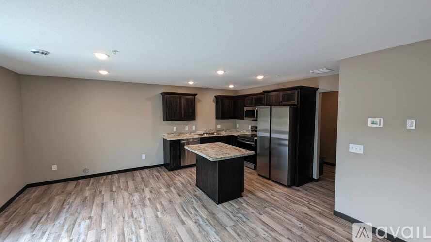 A kitchen with a wooden floor and a refrigerator.
