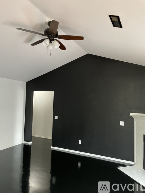 A room with a ceiling fan and a black floor.