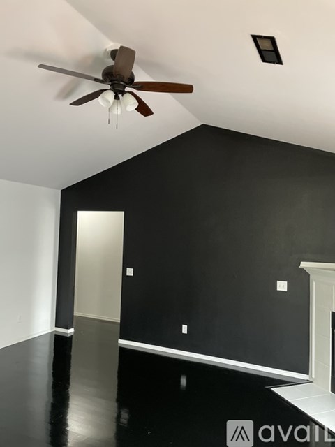 A room with a ceiling fan and a black floor.
