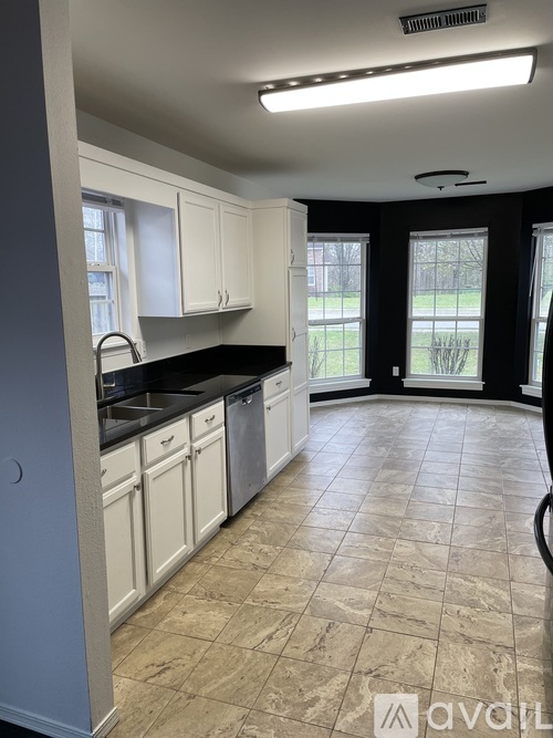A kitchen with white cabinets and a tiled floor.