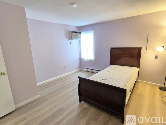 A bedroom with a bed, lamp, and window.