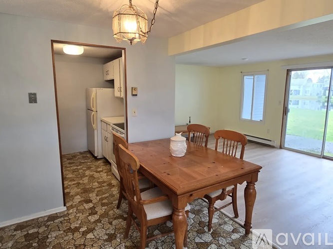 A kitchen with a table and chairs in the foreground and a refrigerator in the background.