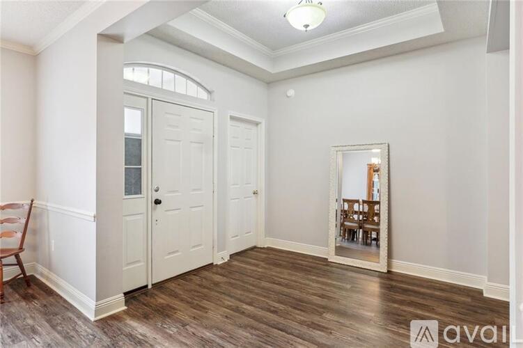 A room with a wooden floor and white walls, with a mirror reflecting a dining area.