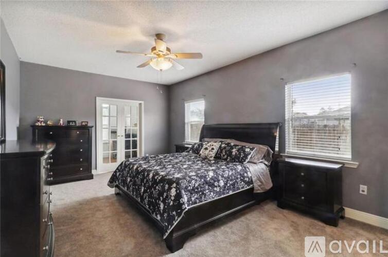 A bedroom with a large bed and a ceiling fan.