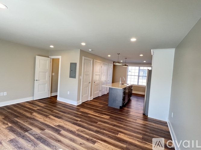 A spacious room with wooden flooring and white walls.