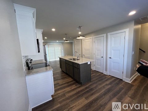 A kitchen with white cabinets and a wooden floor.