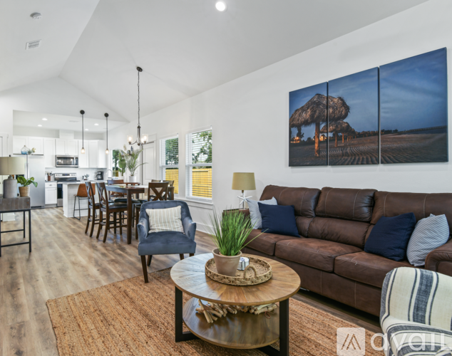 A living room with a brown couch and a large painting on the wall.