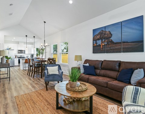 A living room with a brown couch and a large painting on the wall.