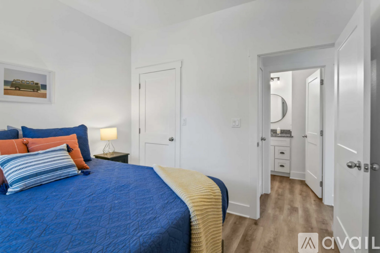 A bedroom with a blue bedspread and a painting on the wall.