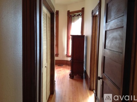 A hallway with a wooden floor and a brown door.