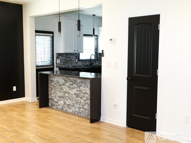 A kitchen with a black door and a stone counter.